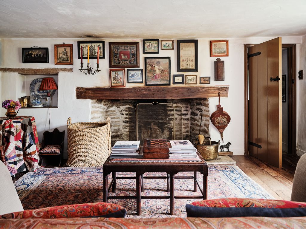 A stool recovered in an antique djadjim rug stands on another antique djadjim from Gallery Yacou. On the wall above the...