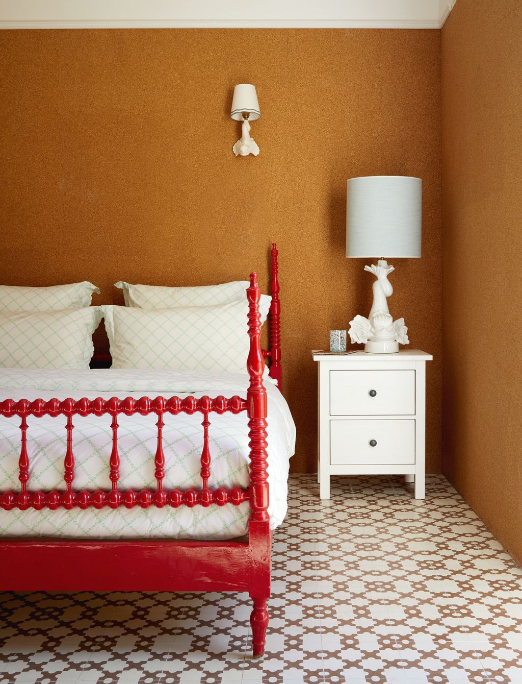Corklined walls and Mosaic Factory tiles are the backdrop for a vintage bed painted in red gloss and a ‘Dolphin lamp and...