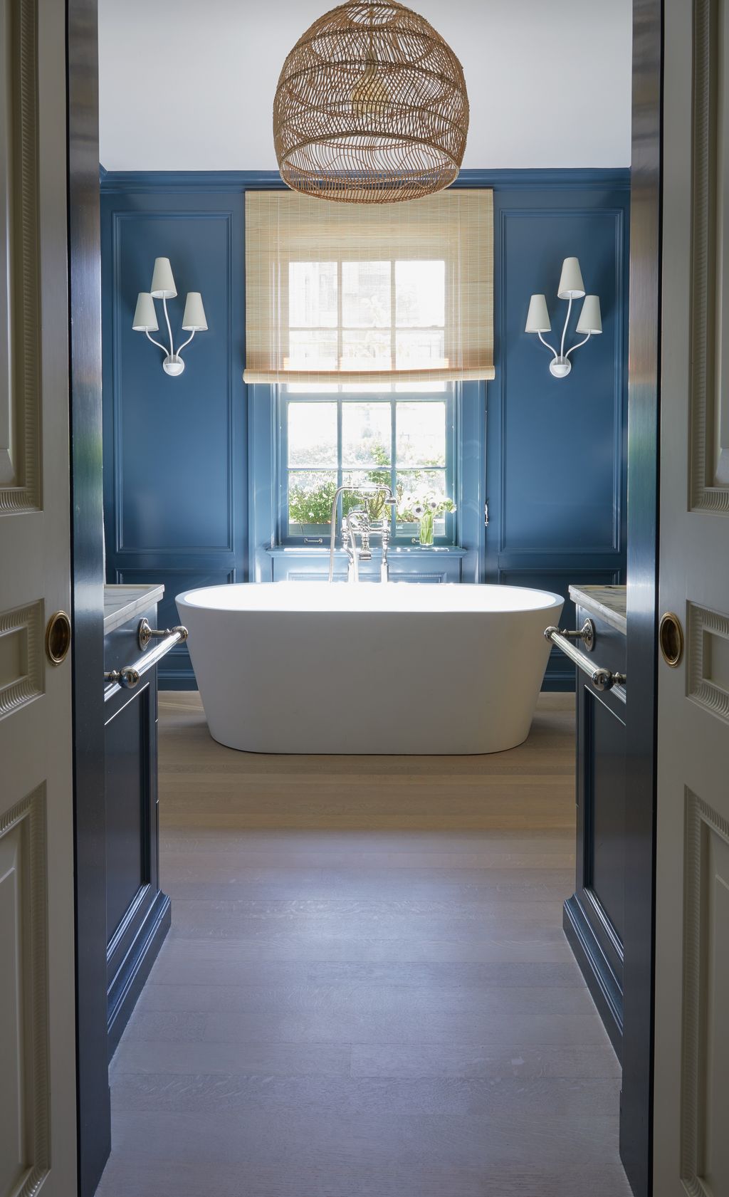 'The principal bath with sconces from Aerin looks out on a wall of green that makes the wraparound terrace feel like a...