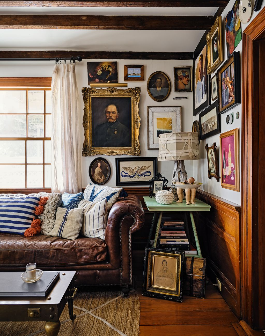 An eclectic array of artworks bought found and gifted over decades fills the walls of the sitting room.
