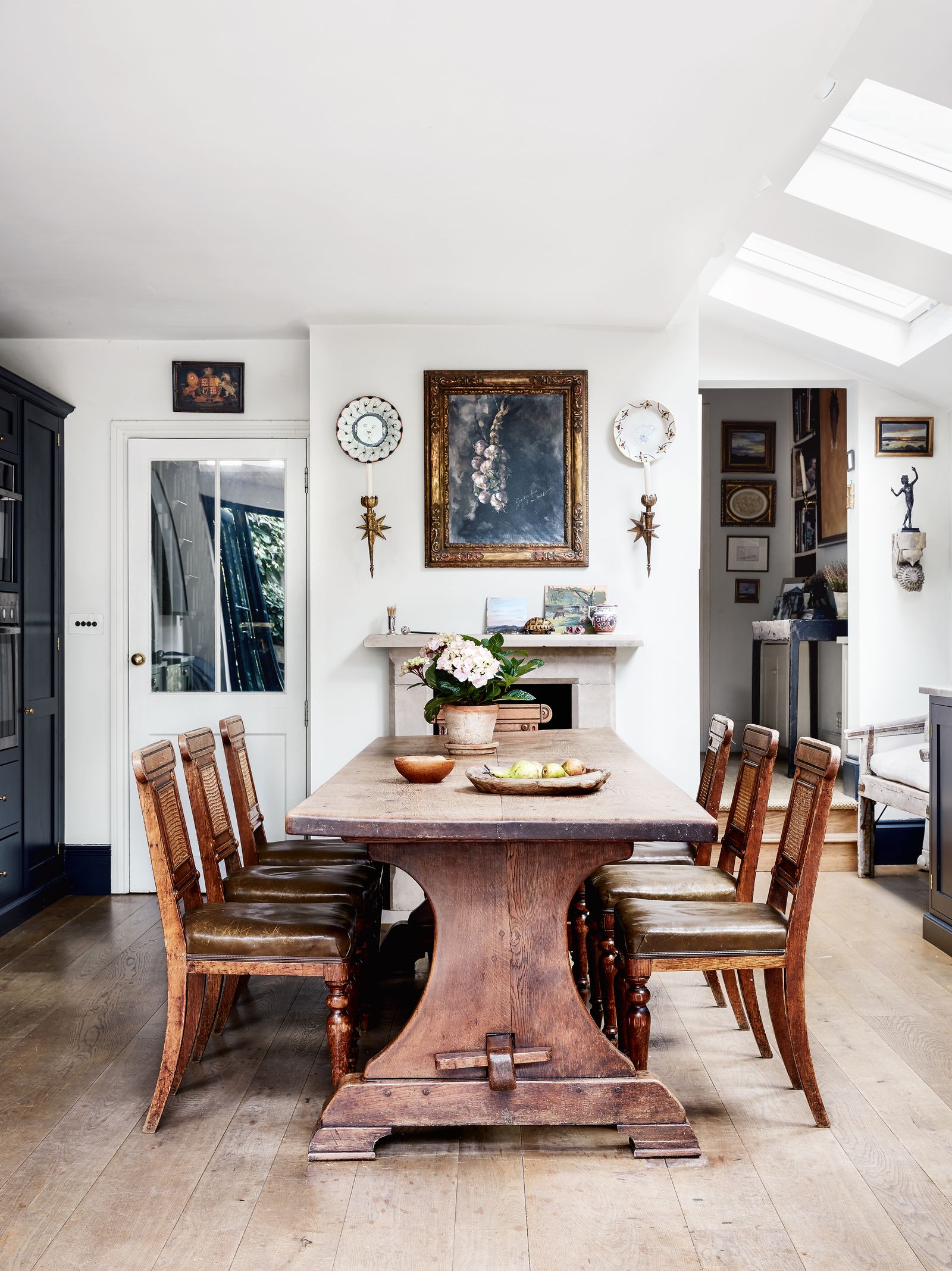 A table from Brownrigg in Tetbury is paired with antique chairs from Westenholz. Above the chimneypiece is a painting by...