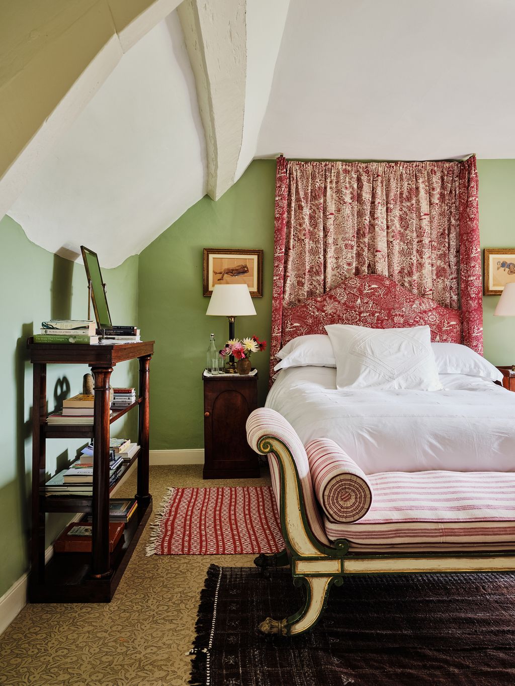 In this bedroom green wall in a colour by Papers  Paints is a foil for the red bed tester in a fabric by Katherine Ireland.