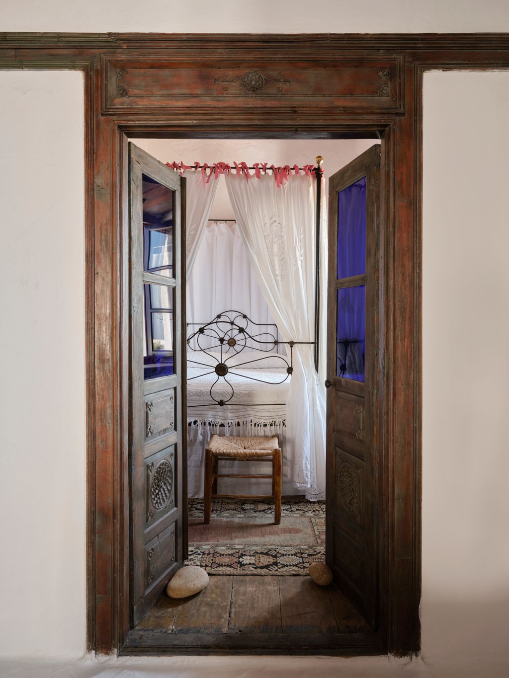 In a guest bedroom off the white room that has an iron fourposter bed hung with handemboidered curtain from northern...
