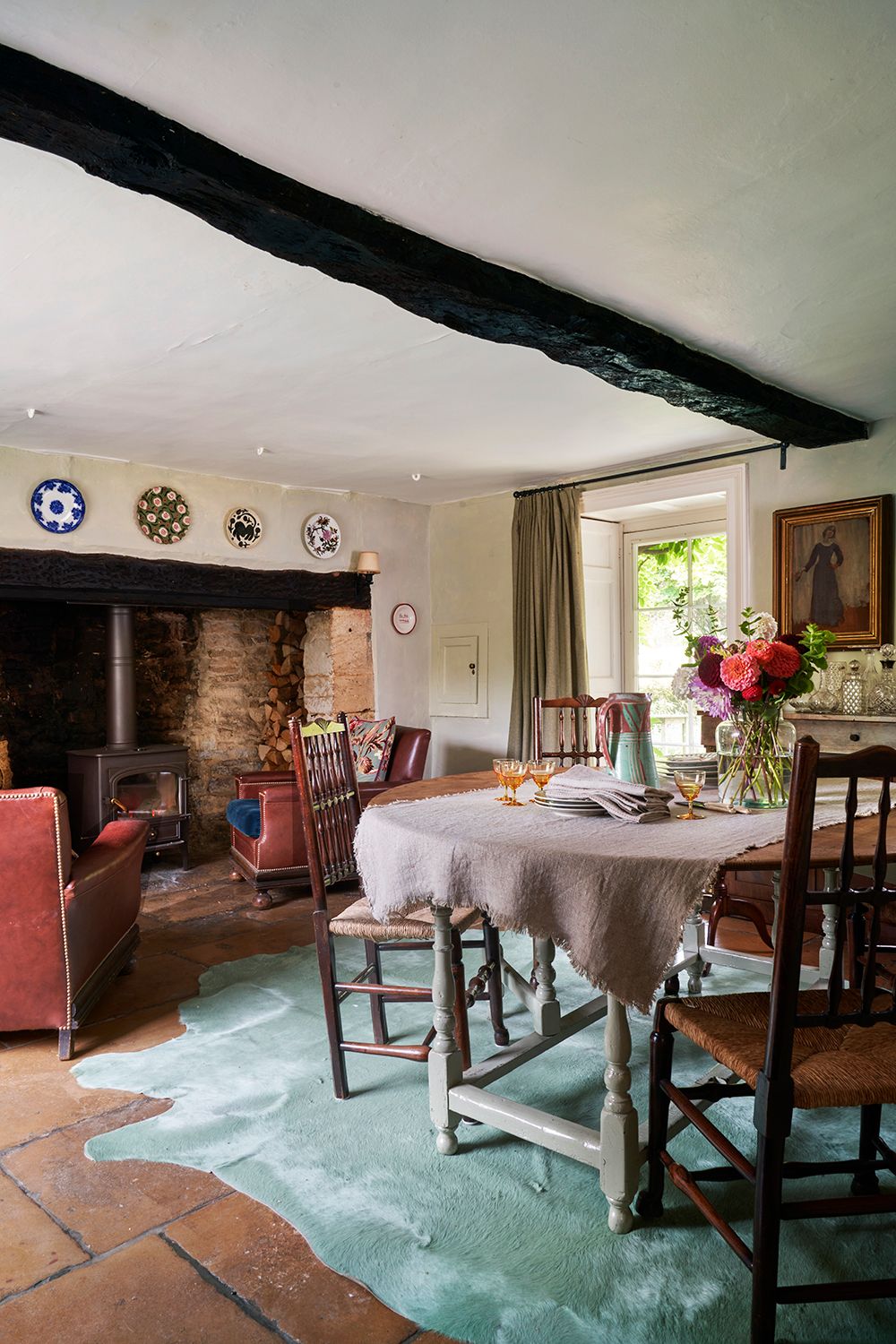 A duck egg blue cowhide Penelope Chilvers rug lies over the original flagstones. The woodburner was added in for extra...
