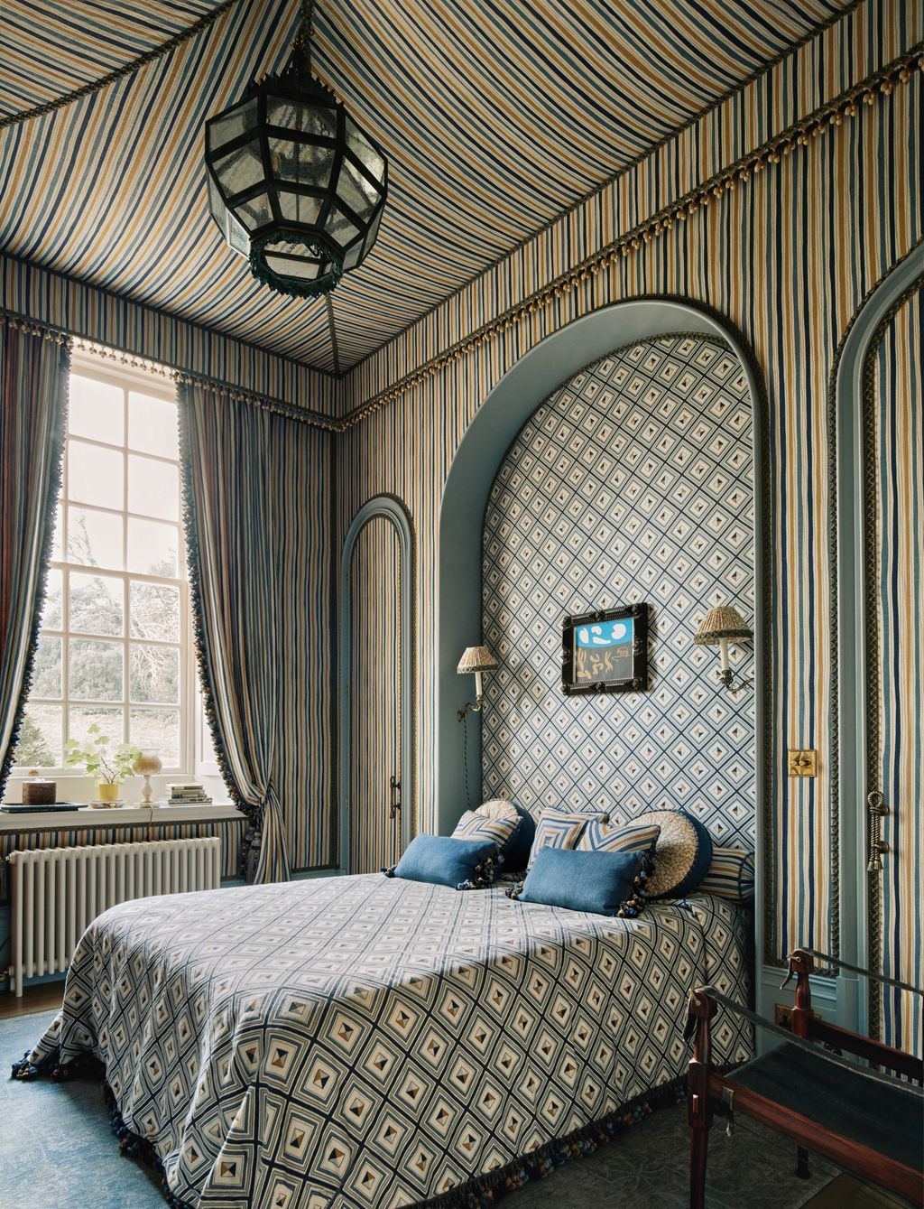 In the spare room of Martin Brudnizki's flat in Sussex striped ‘Boundary fabric in ochre on the walls contrasts with...