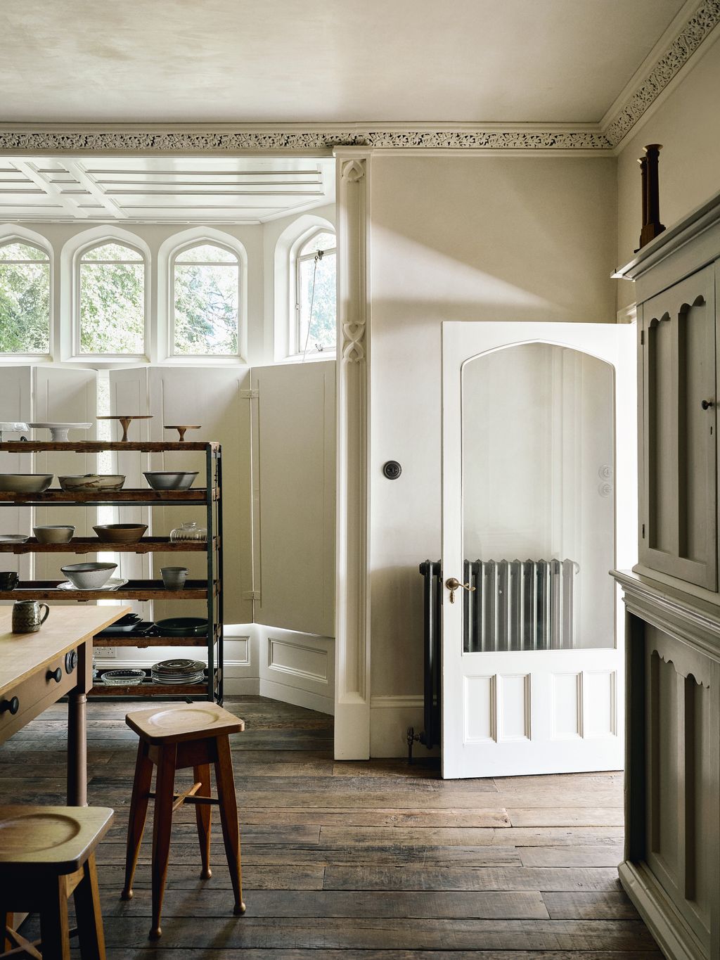 Midcentury ceramics and glassware are displayed on a vintage bread trolley in the window bay.