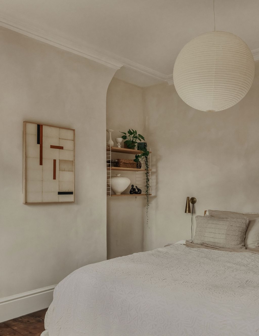 The main bedroom is calm and soft with limewash walls and more art by Lucy Naughton.