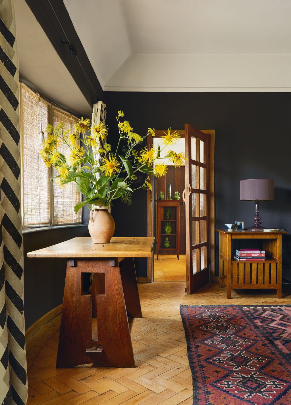 Image may contain Lamp Corner Indoors Interior Design Home Decor Rug Wood Hardwood Desk Furniture Table and Door