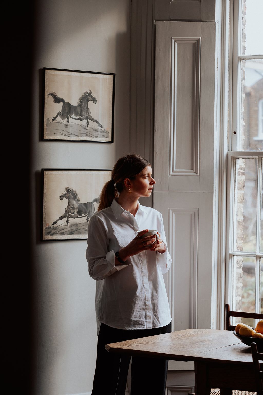 Image may contain Adult Person Chair Furniture Bread Food Art Painting Desk Table Blouse Clothing Face and Head