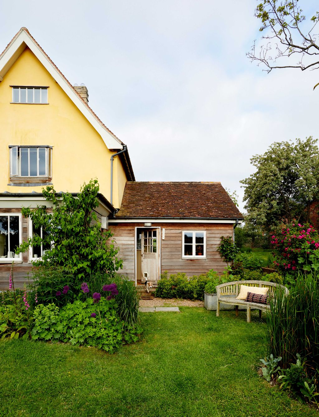 Image may contain Architecture Building Cottage House Housing Grass Plant Backyard Nature Outdoors Yard and Bench