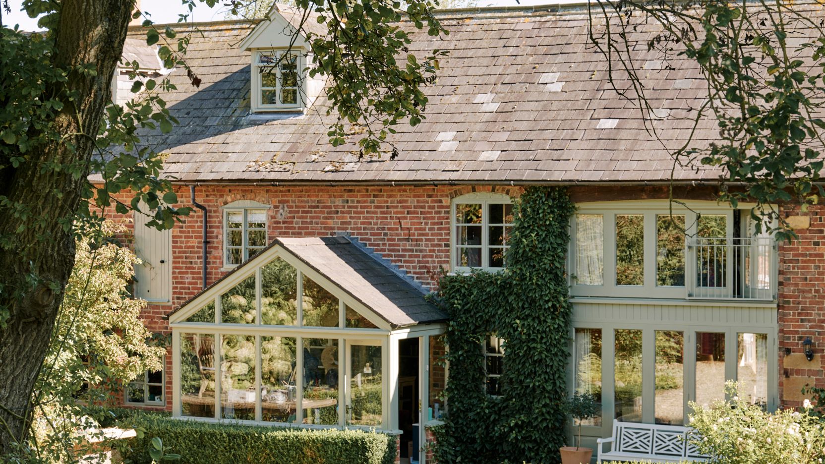 Image may contain Plant Architecture Building Cottage House Housing Grass Animal Canine Dog Mammal Pet and Bench