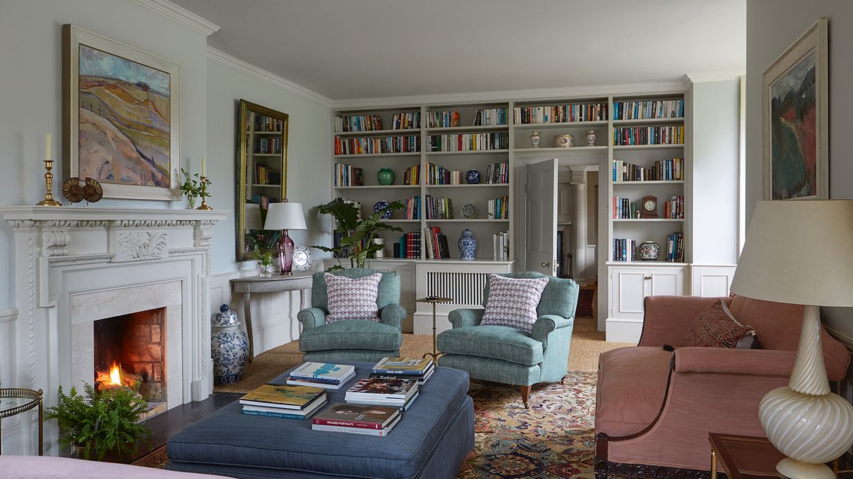 Image may contain: Home Decor, Lamp, Furniture, Fireplace, Indoors, Architecture, Building, Living Room, Room, and Book