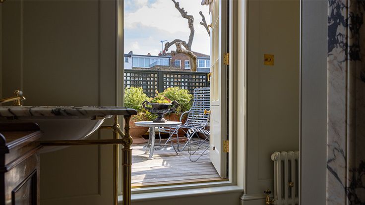 Image may contain: Architecture, Balcony, Building, Desk, Furniture, Table, Home Decor, Rug, Plant, and Chair