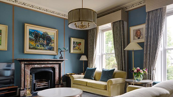 Image may contain: Lamp, Couch, Furniture, Home Decor, Art, Painting, Fireplace, Indoors, Person, Table, and Architecture