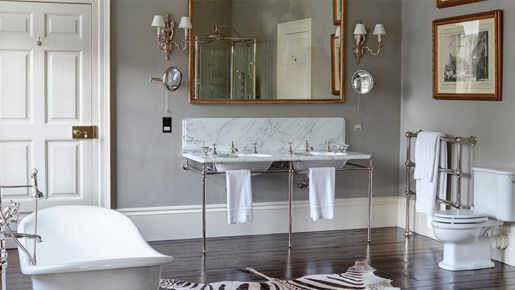 Image may contain: Home Decor, Rug, Lamp, Art, Painting, Bathroom, Indoors, Room, Toilet, Sink, Bathing, Bathtub, and Person