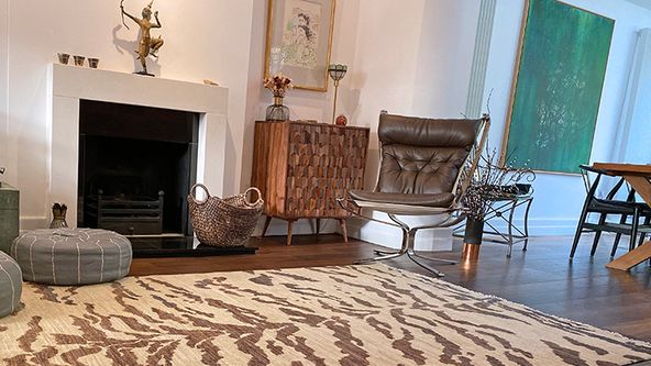 Image may contain: Home Decor, Rug, Chair, Furniture, Art, Painting, Person, Accessories, Bag, Handbag, and Fireplace