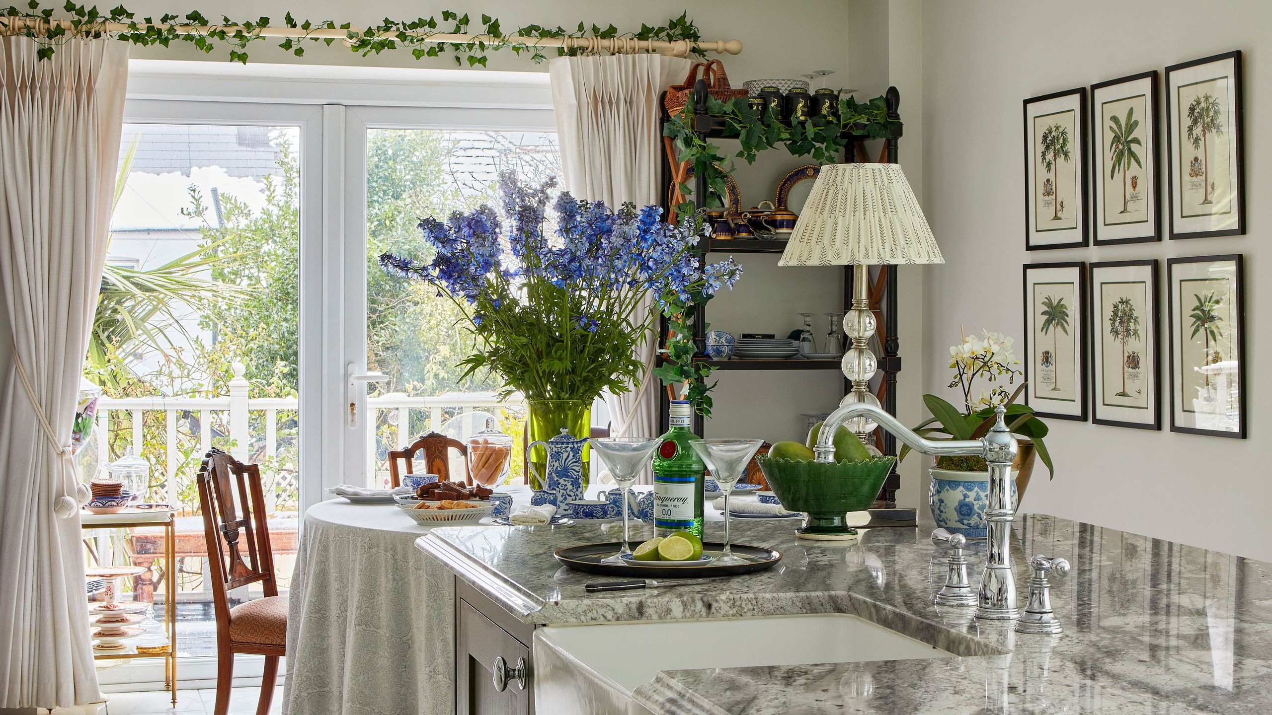 Image may contain: Indoors, Interior Design, Chair, Furniture, Kitchen, Lamp, Plate, Desk, Table, Flower, Plant, and Sink