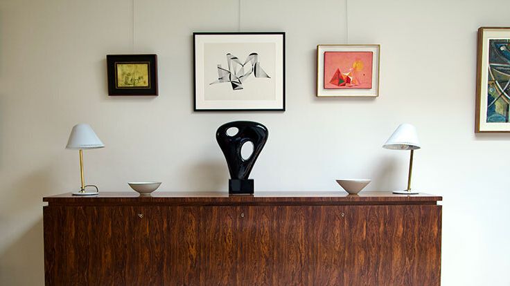 Image may contain: Furniture, Sideboard, Lamp, Table Lamp, Indoors, Interior Design, Wood, Art, Painting, Cabinet, and Table