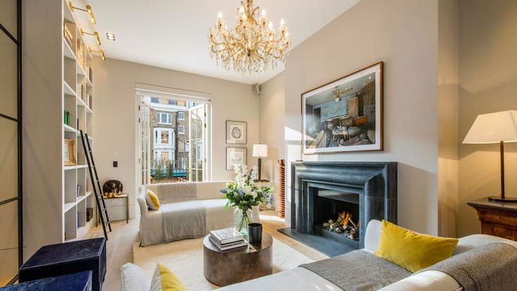 Image may contain: Home Decor, Lamp, Art, Painting, Couch, Furniture, Chandelier, Fireplace, Indoors, Desk, Table, and Book