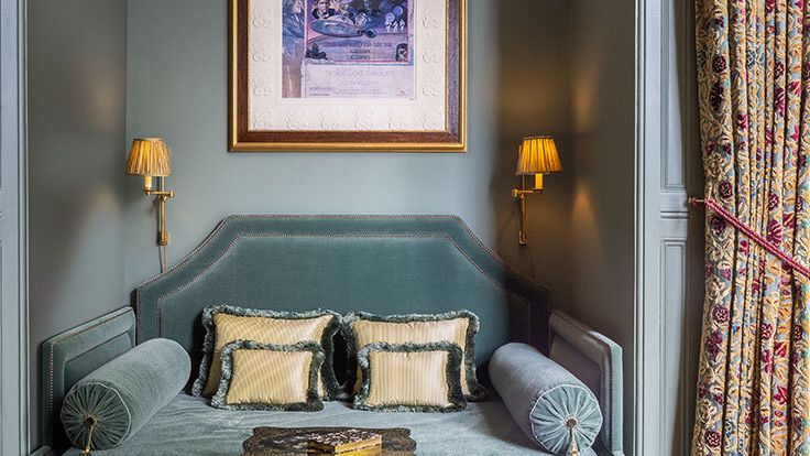 Image may contain: Lamp, Art, Painting, Cushion, Home Decor, Couch, Furniture, Person, Pillow, Table Lamp, Bed, and Indoors