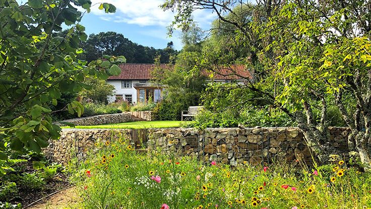 Image may contain: Architecture, Building, Cottage, House, Housing, Villa, Bench, Furniture, Plant, Vegetation, and Garden