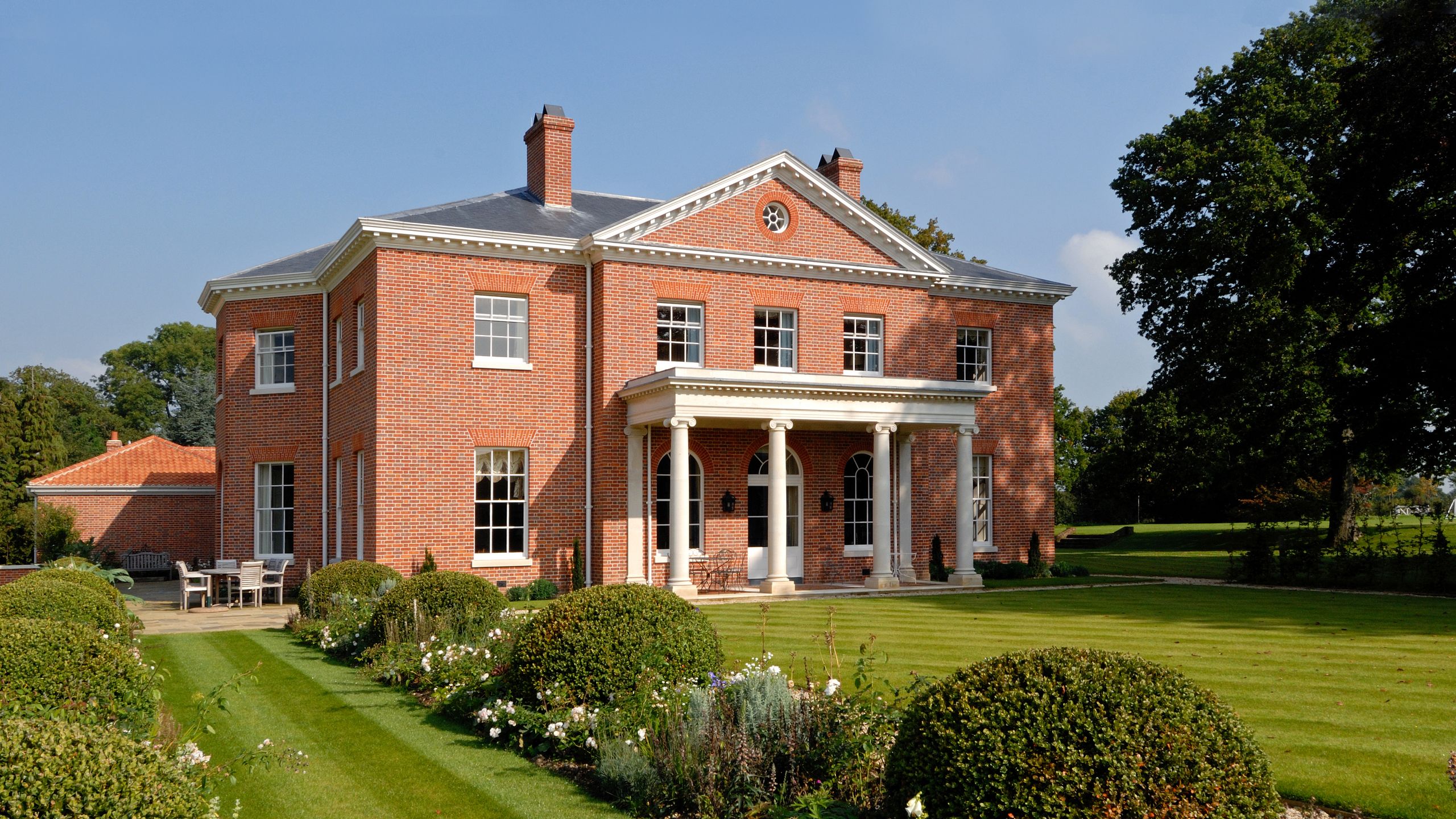 Image may contain: Architecture, Building, Housing, House, Grass, Plant, Chair, Furniture, Manor, and Person