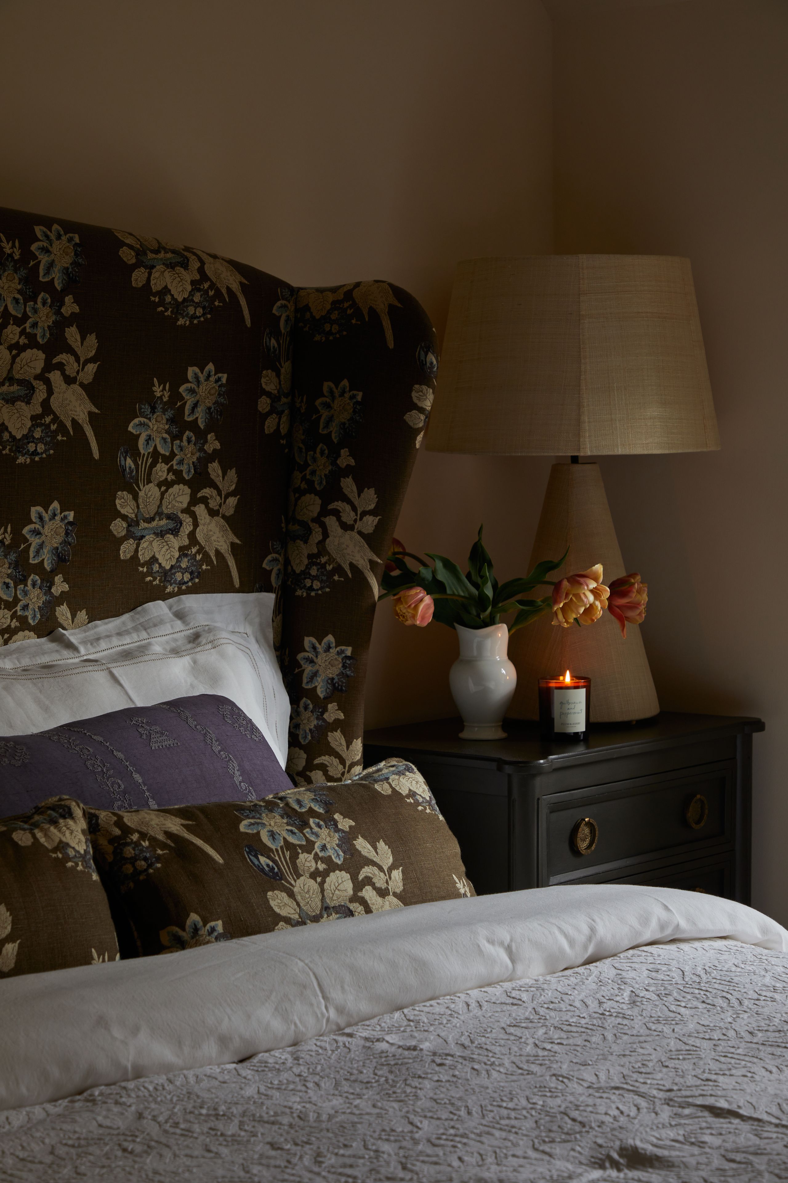 Image may contain: Cushion, Home Decor, Lamp, Table Lamp, Pillow, Plant, Indoors, Interior Design, Candle, Furniture, and Bed