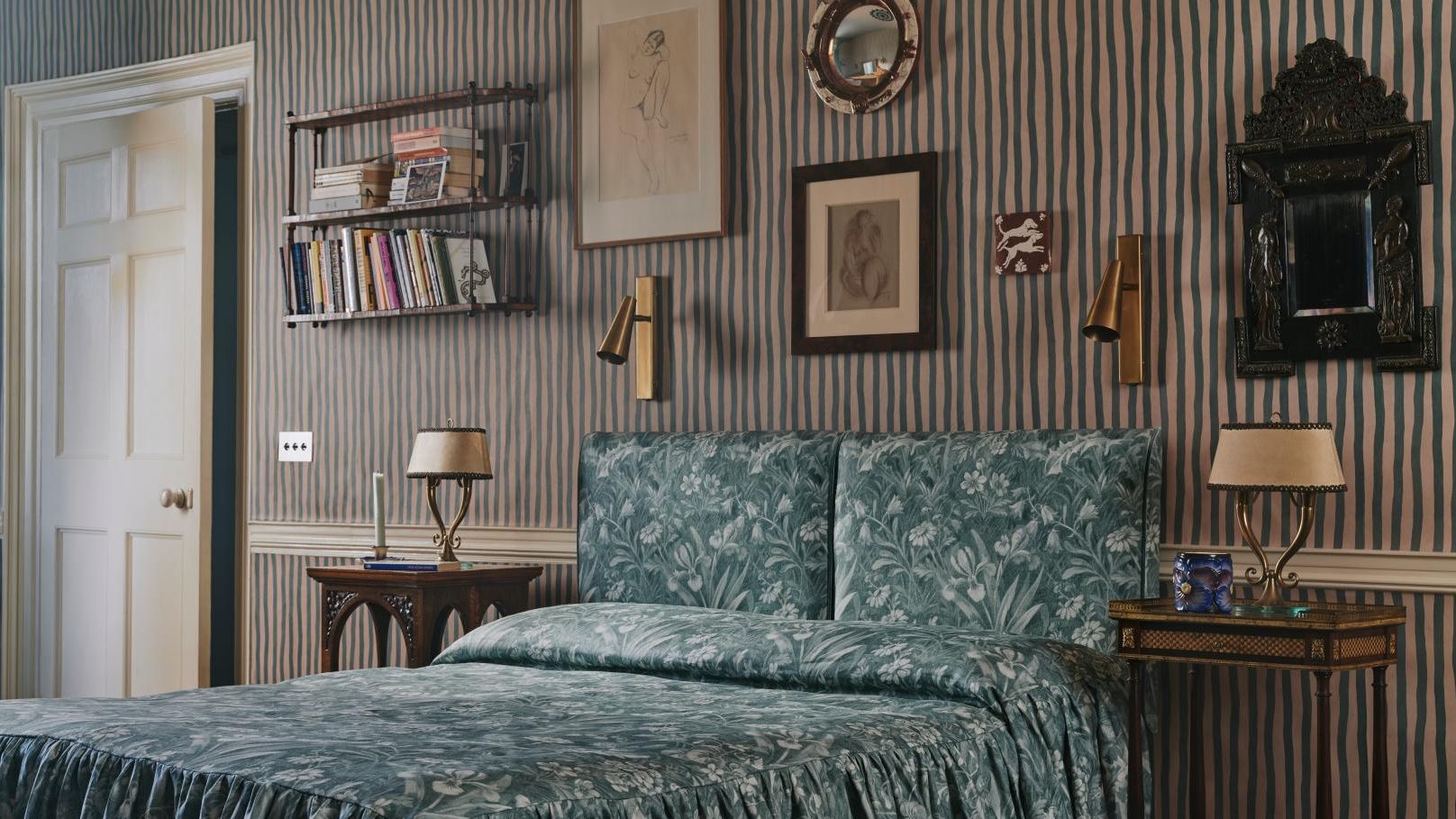 Image may contain: Indoors, Interior Design, Lamp, Bed, Furniture, Desk, Table, Art, Painting, Table Lamp, and Person