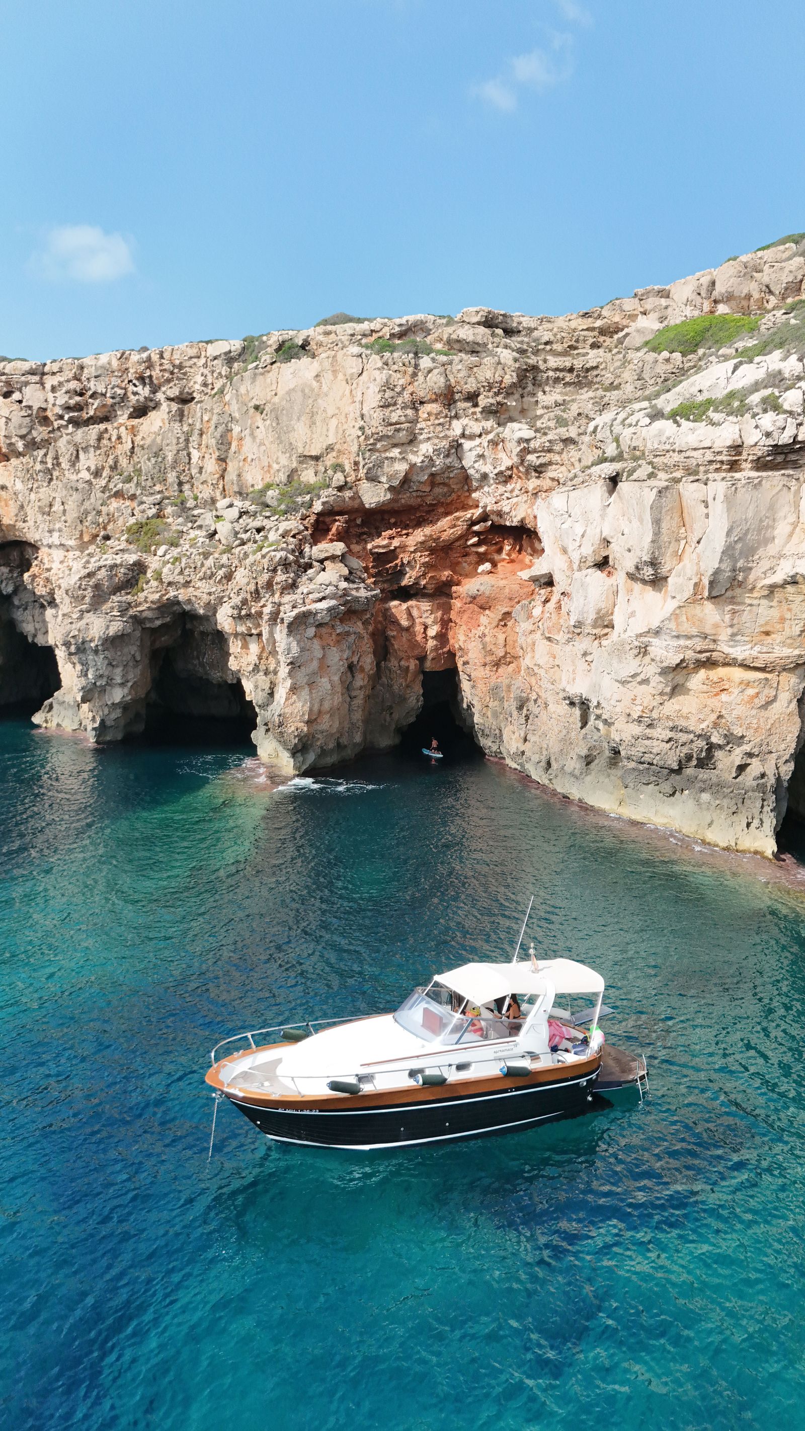 Image may contain Transportation Vehicle Yacht Rock Boat Cliff Nature Outdoors Sea Water Cave Coast and Cove