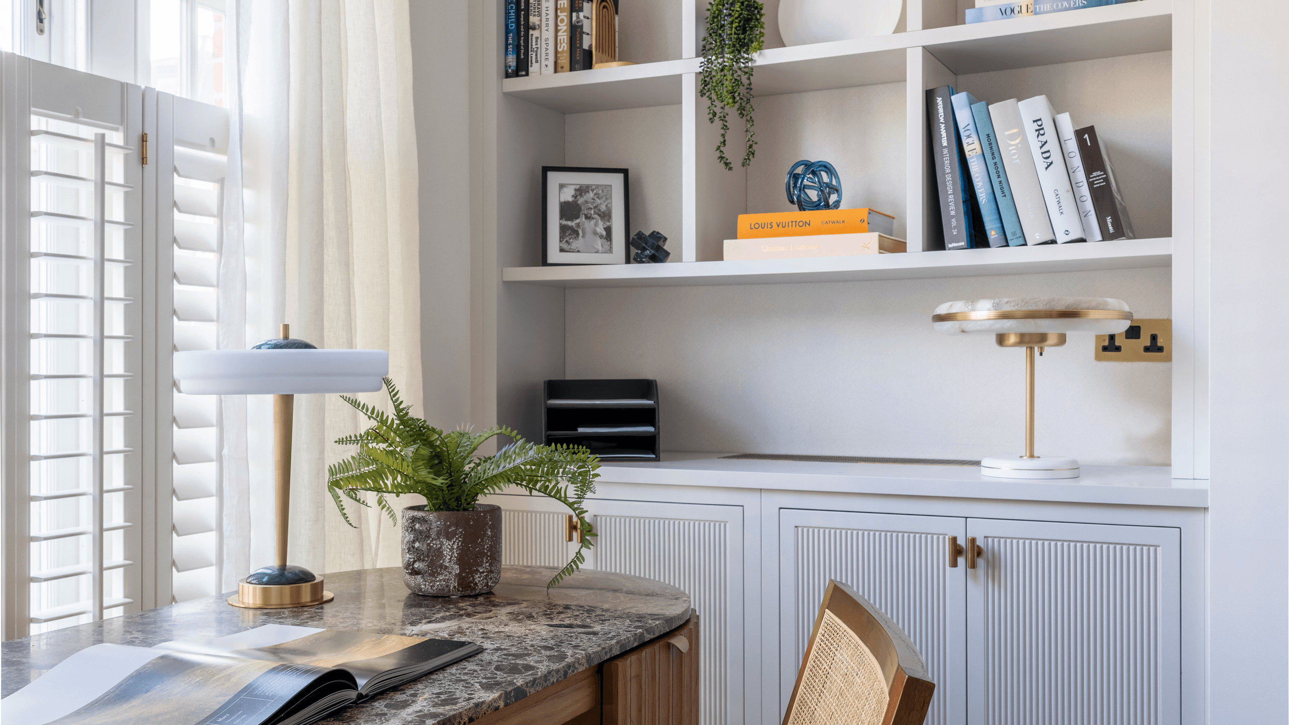 Image may contain: Indoors, Interior Design, Furniture, Table, Plant, Chair, Shelf, Lamp, Bookcase, Wood, and Window