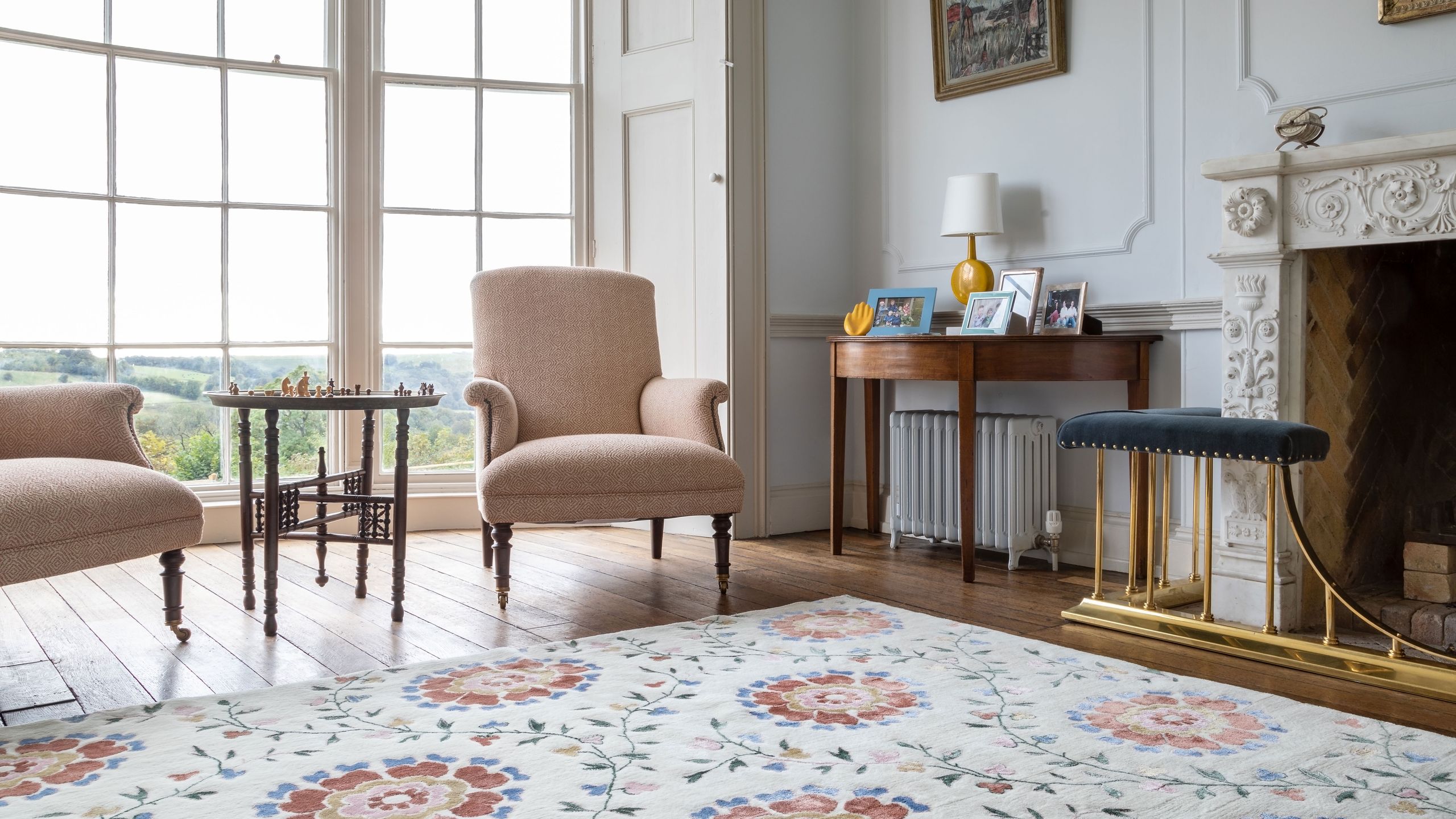 Image may contain: Home Decor, Rug, Lamp, Chair, Furniture, Desk, Table, Fireplace, Indoors, Art, Painting, and Architecture