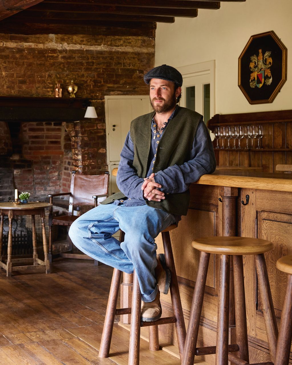 Image may contain Person Sitting Adult Clothing Hat Desk Furniture Table Art Painting Chair Wood and Pants