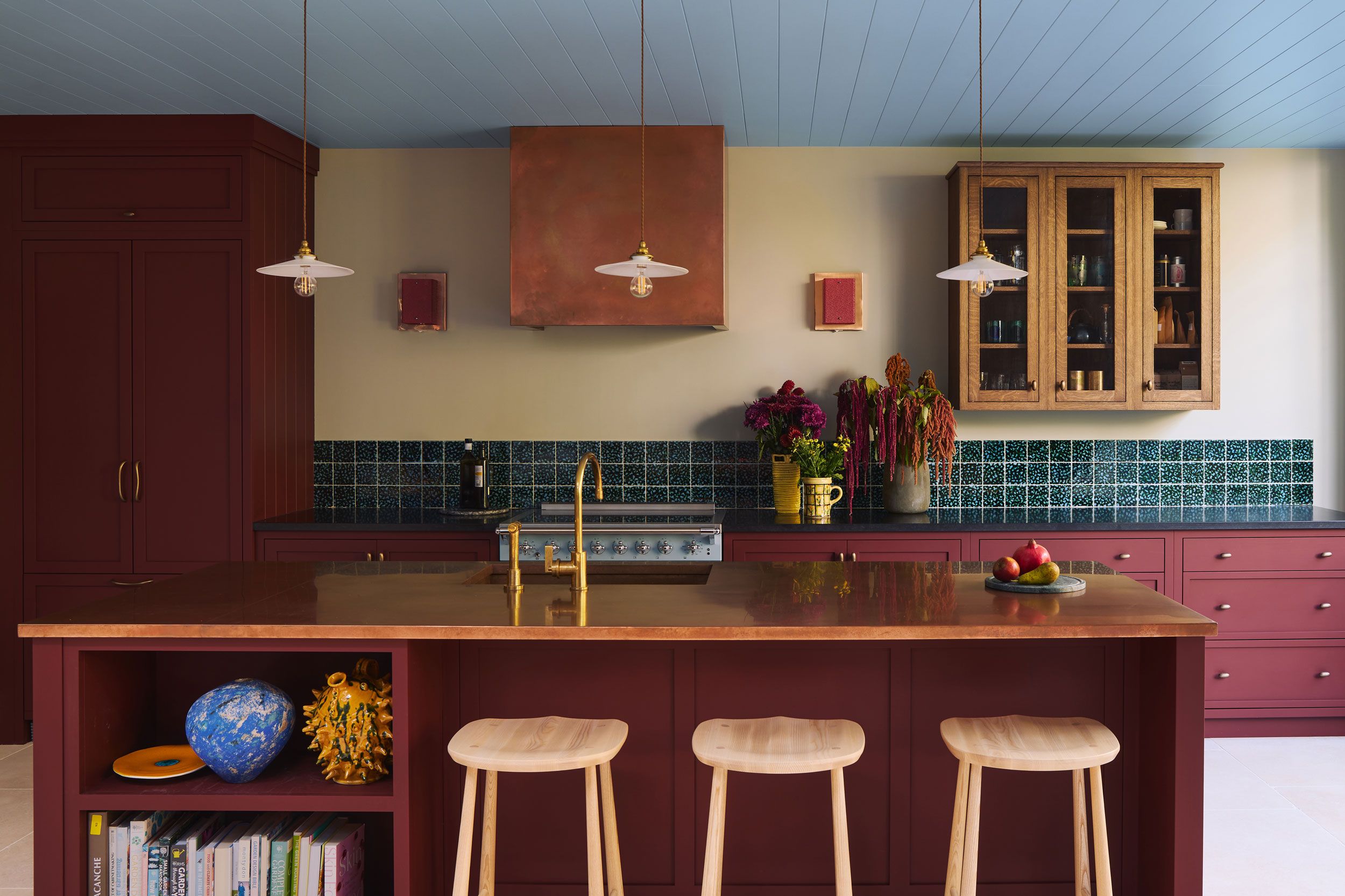 Image may contain: Indoors, Interior Design, Lamp, Kitchen, Kitchen Island, Furniture, Cabinet, Plate, Cup, and Bar Stool