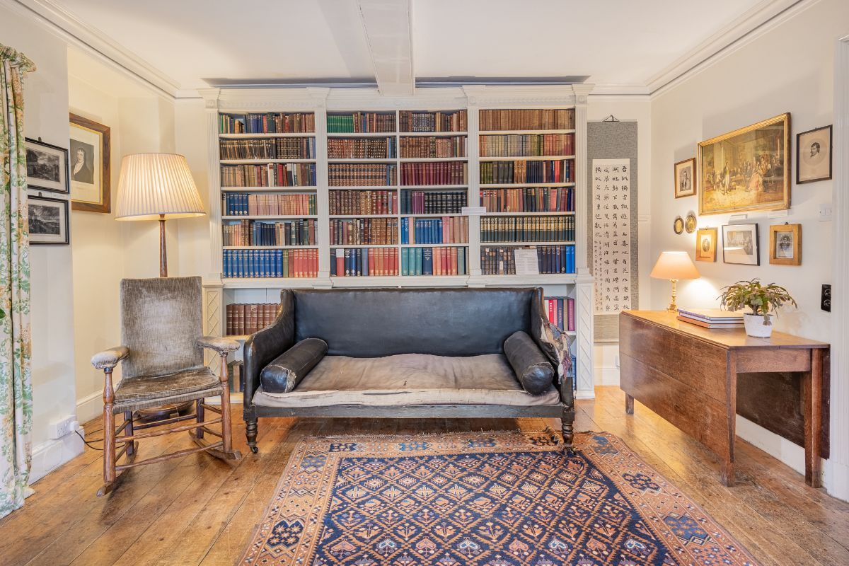 Image may contain Lamp Plant Home Decor Chair Furniture Couch Rug Art Painting Person Desk Table and Bookcase