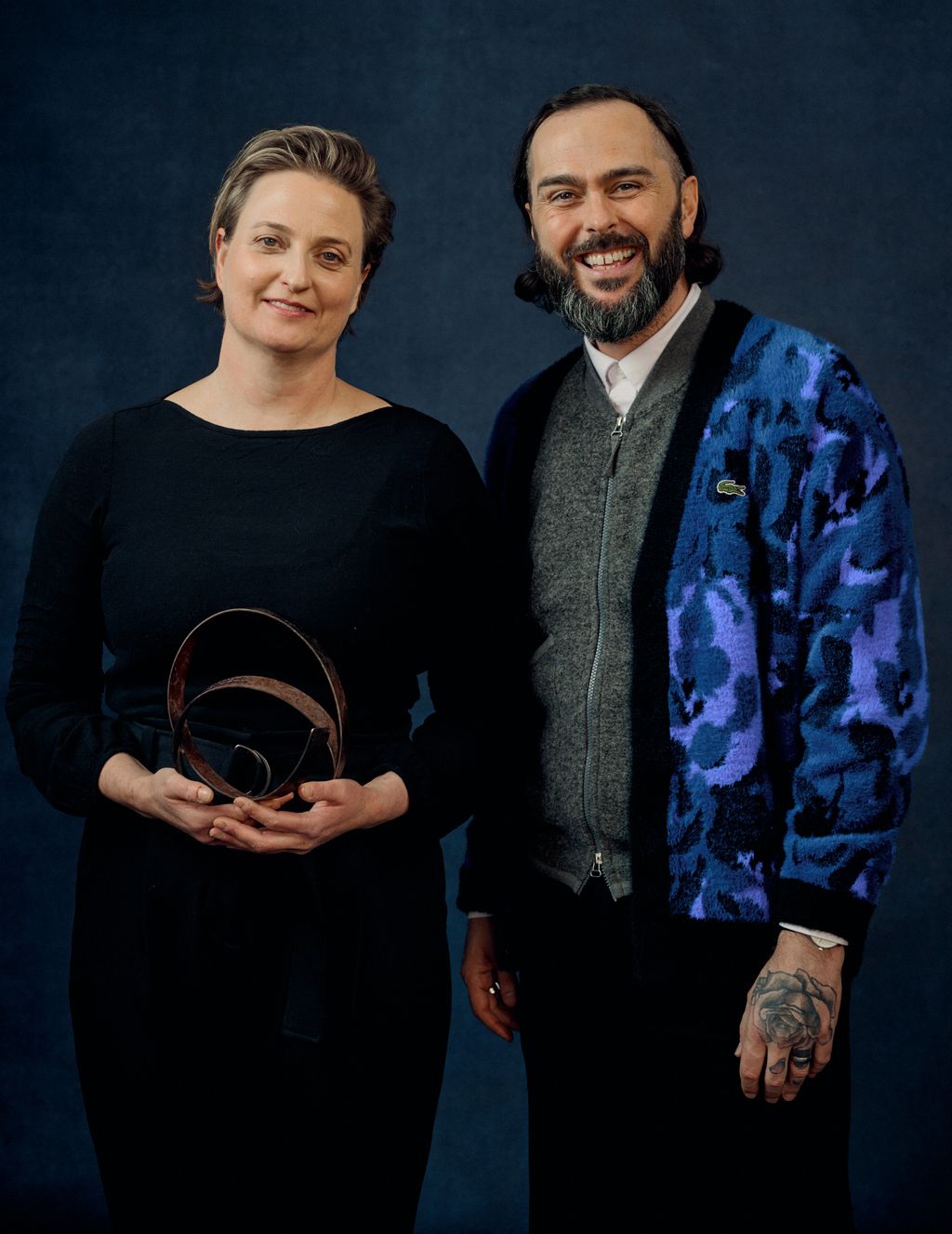 Image may contain Mitch Mullany Clothing Coat Jacket Long Sleeve Sleeve Blazer Pants Adult Person Face and Happy