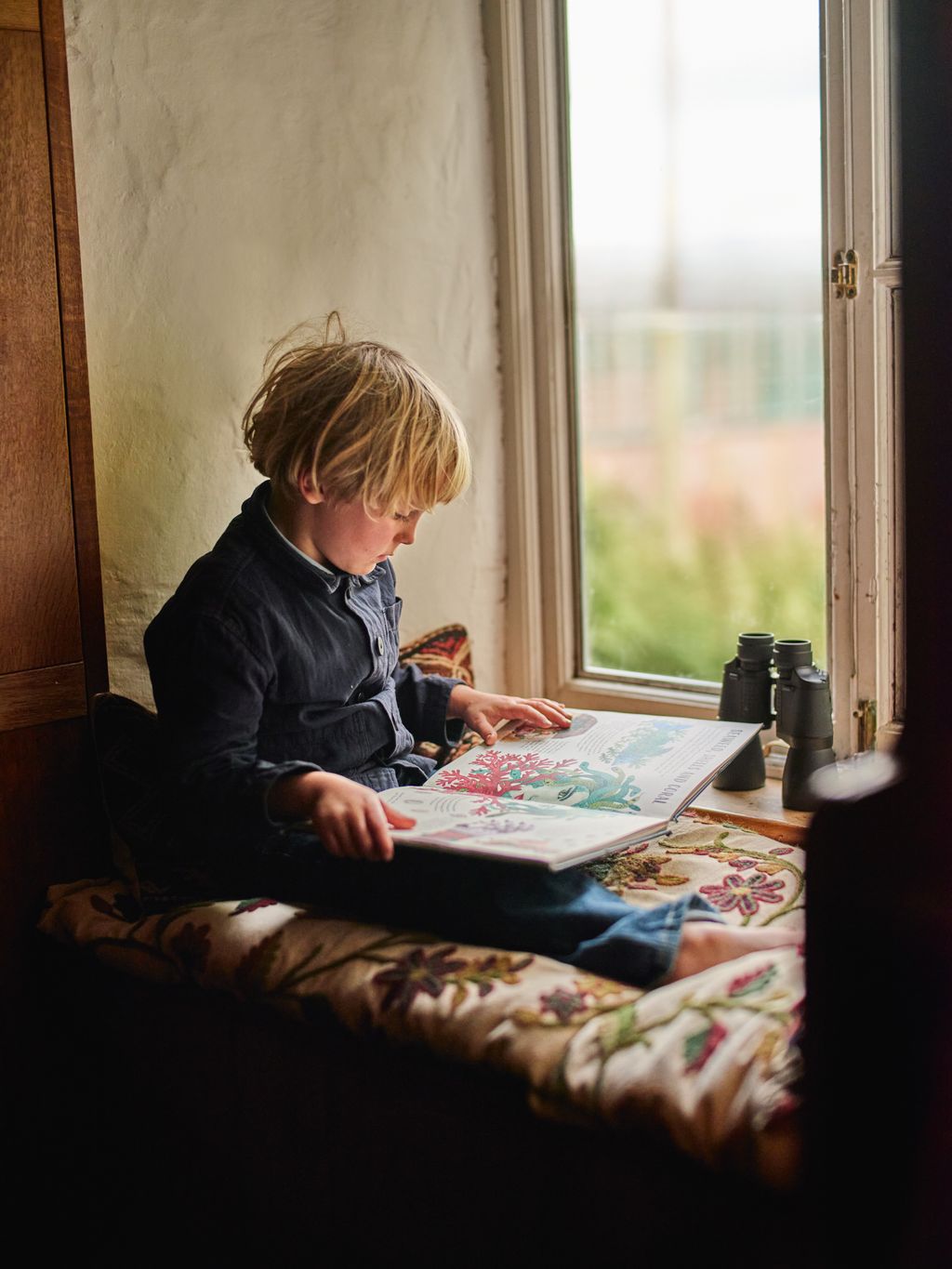 Image may contain Person Sitting Reading Child Window and Windowsill