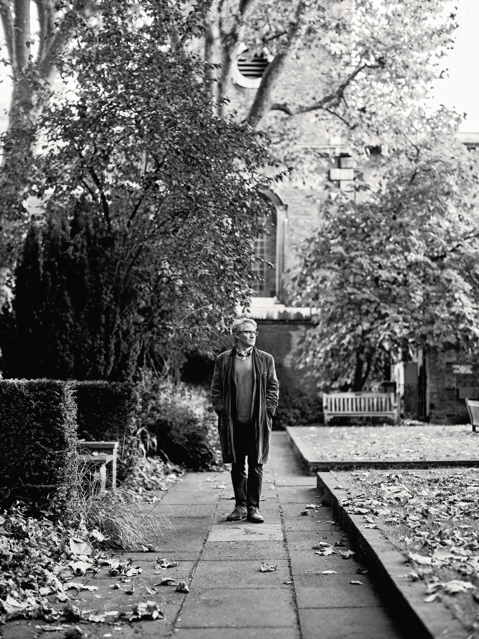 Image may contain Person Walking Clothing Coat Path Adult Standing Sidewalk Footwear Shoe Plant and Tree