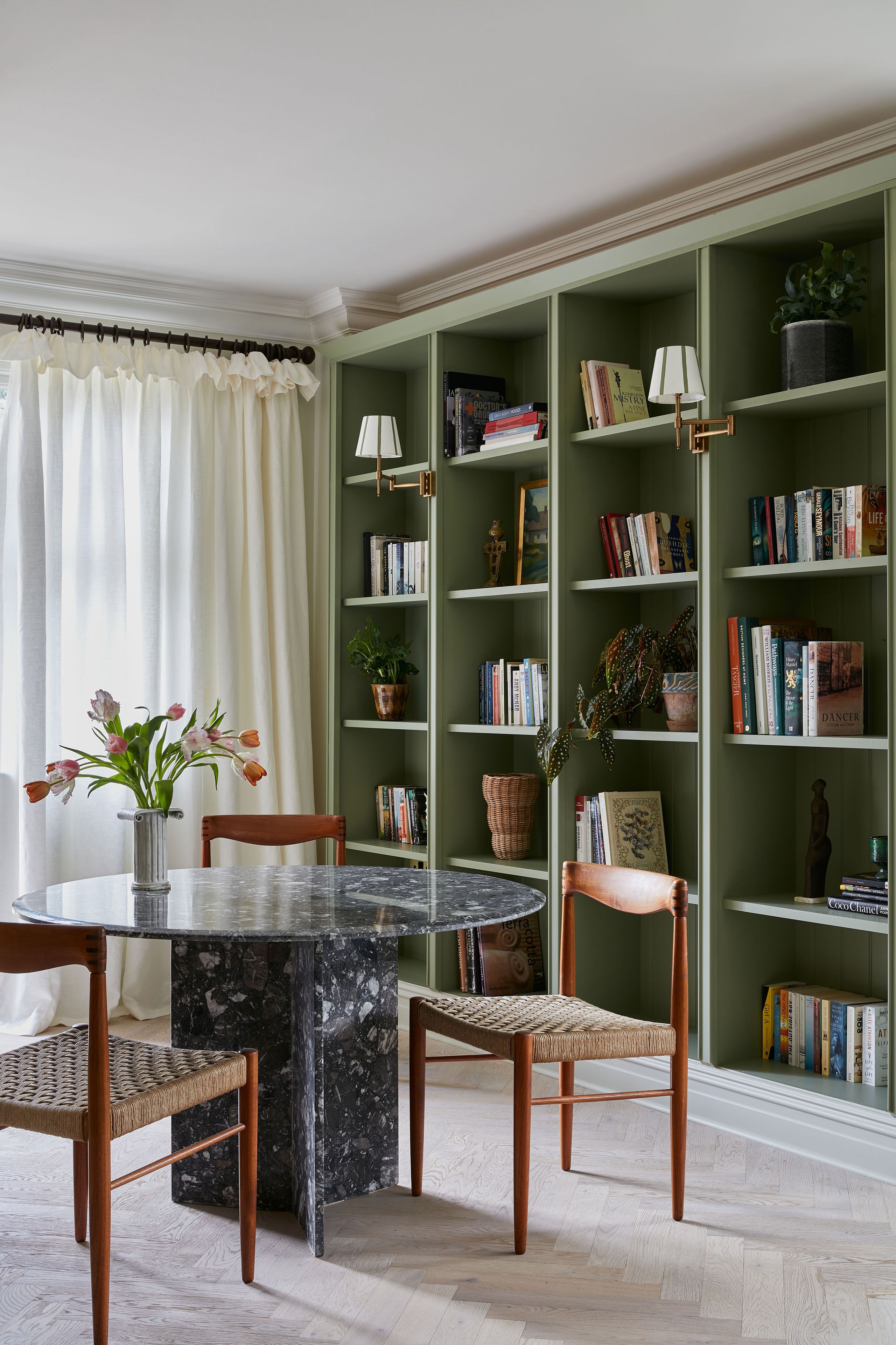 Image may contain: Furniture, Desk, Table, Chair, Plant, Bookcase, Lamp, Person, Art, and Painting