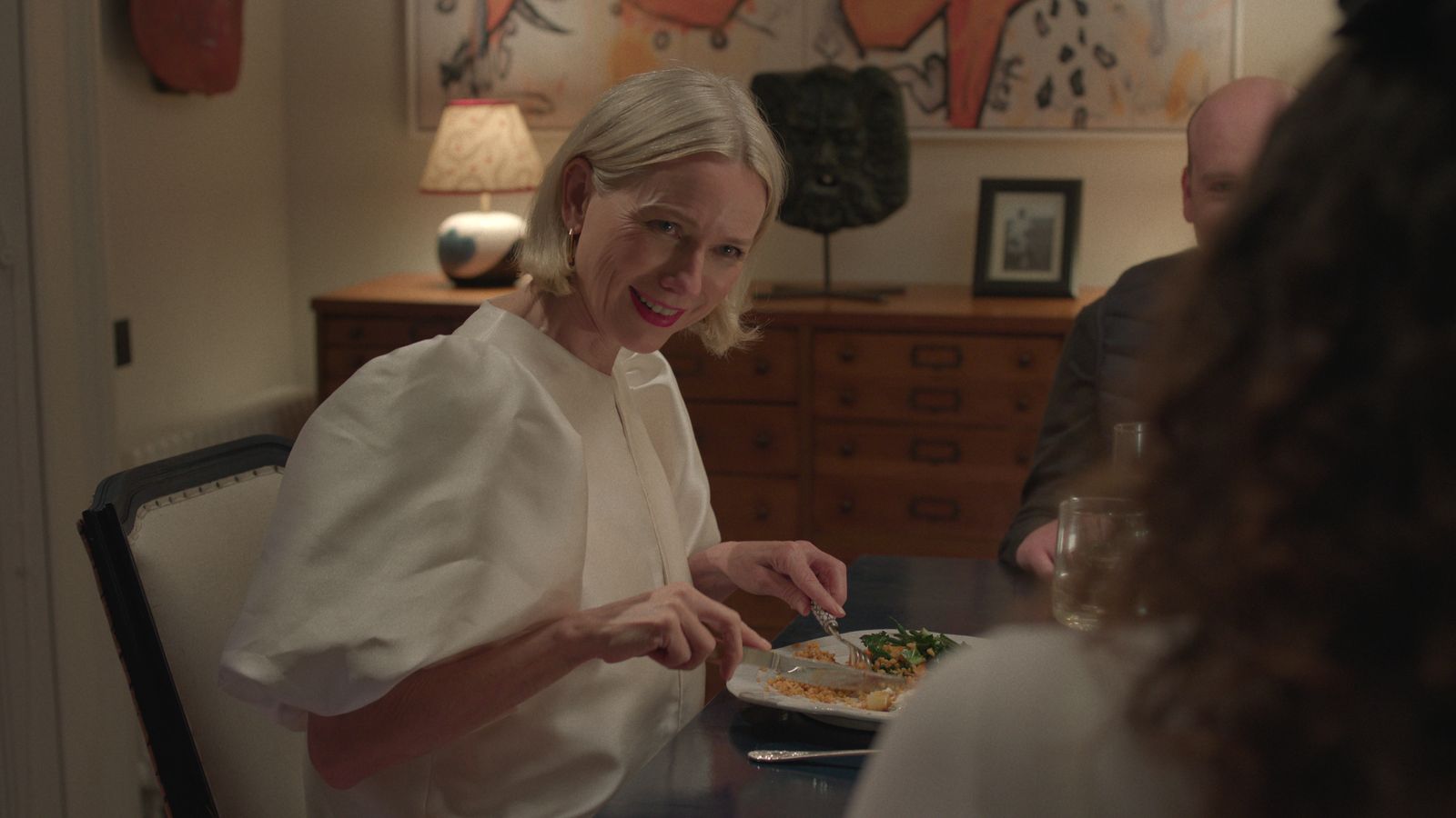 Image may contain Naomi Watts Lamp Dining Table Furniture Table Adult Person Cup Art Painting Plate and Cutlery