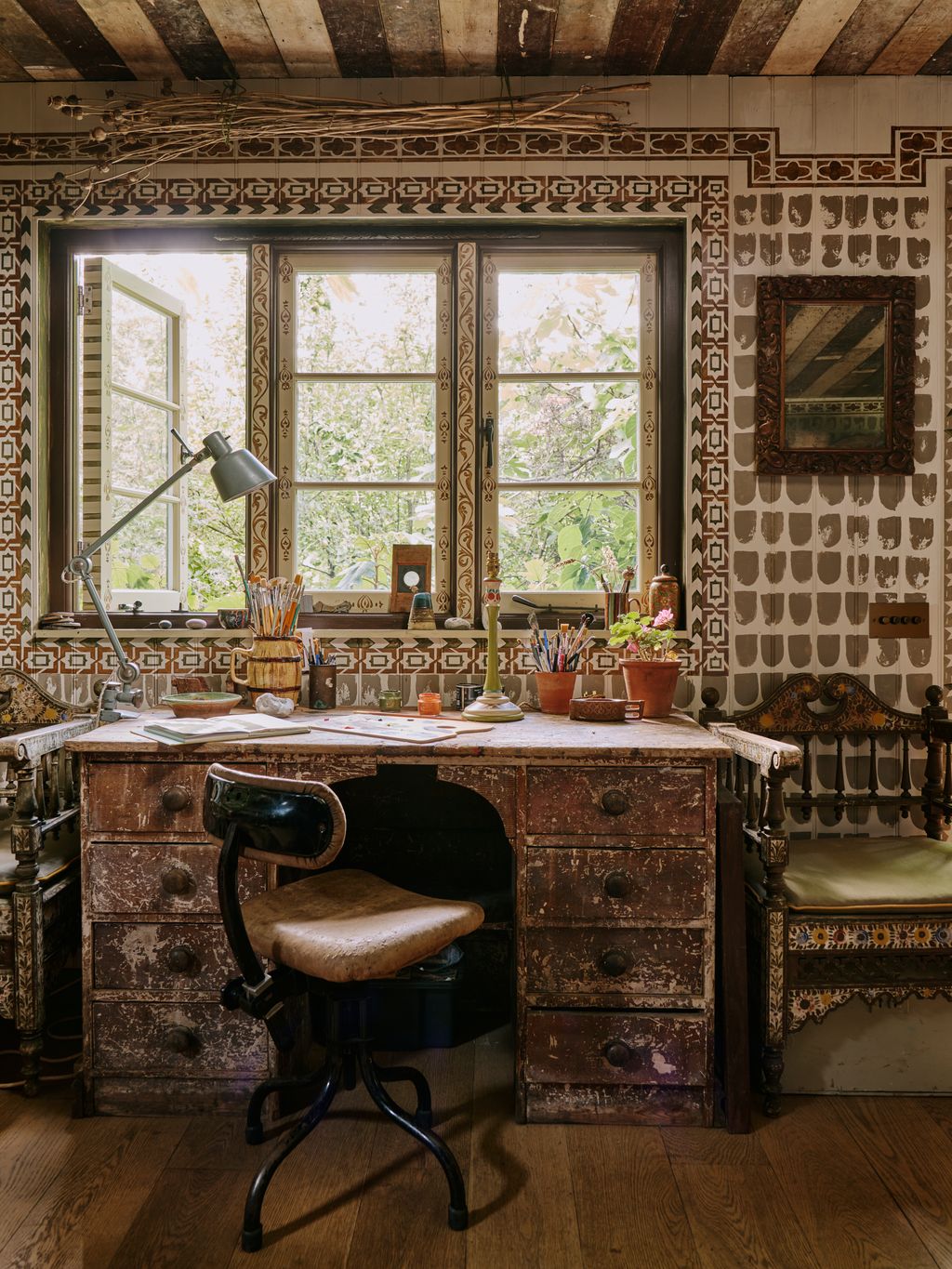 Image may contain Indoors Interior Design Chair Furniture Lamp Desk Table Window Art Painting and Plant