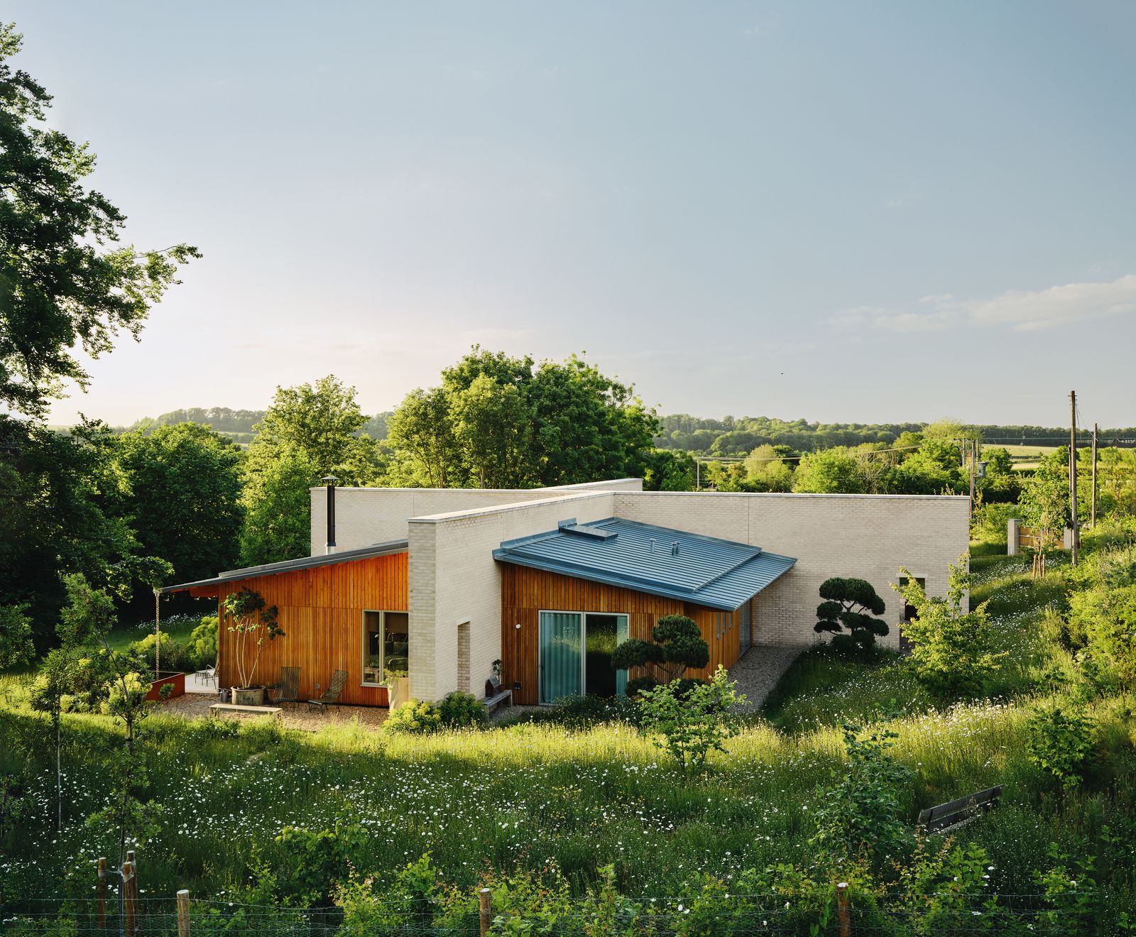 Walls of clay brick intersect to form a broken cruciform that shelters four rectangular timberframed living areas....