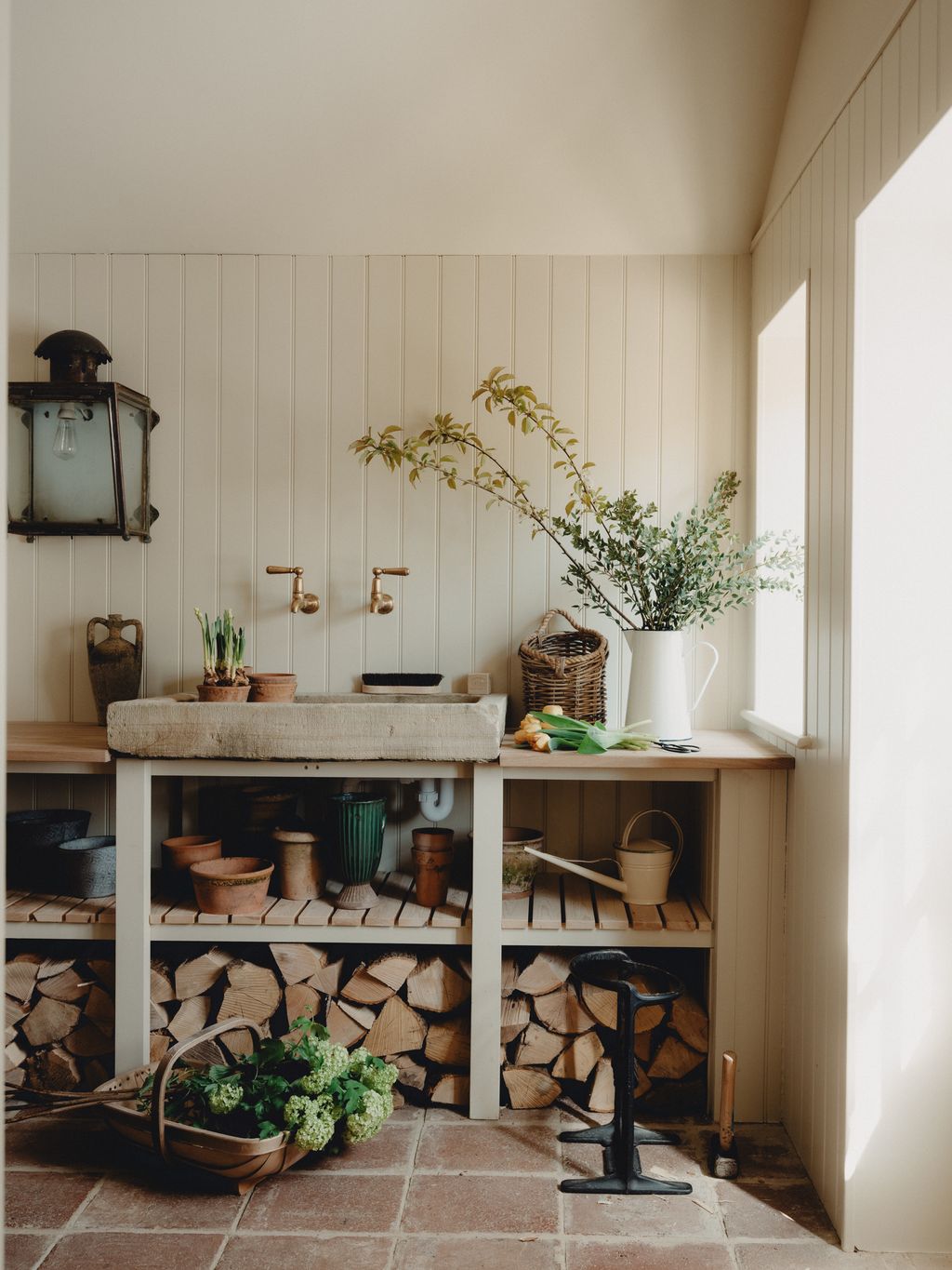The characterful boot room of this quietly elegant Cotswold barn by Berkeley Hawkes has a reclaimed antique stone trough...