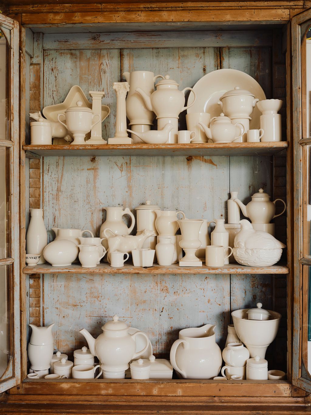 A cupboard in the studio filled with white pottery.