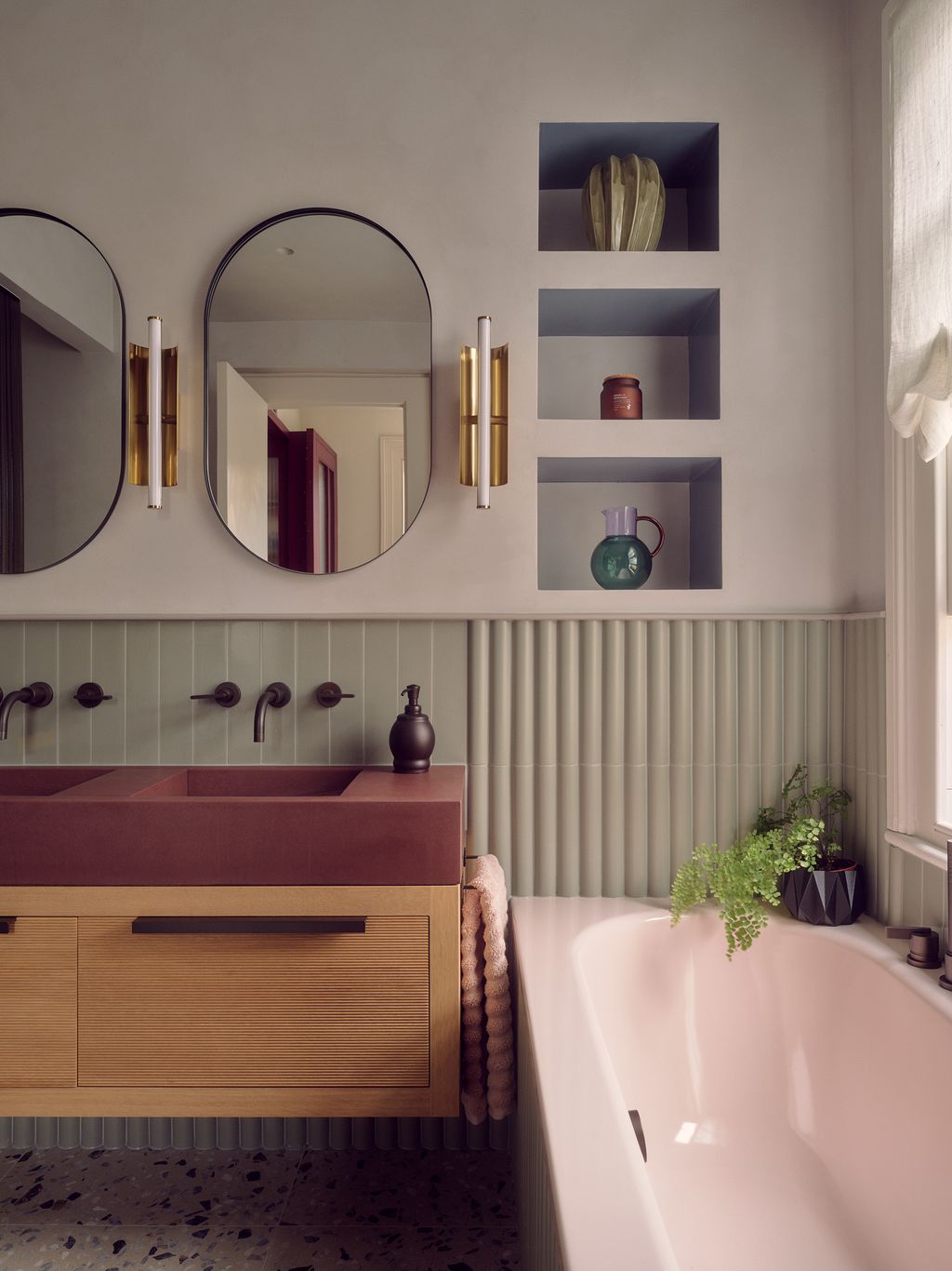Flanking a pair of oval mirrors wall lights from Chelsom echo the elongated shape. The basin is from KAST concrete and...
