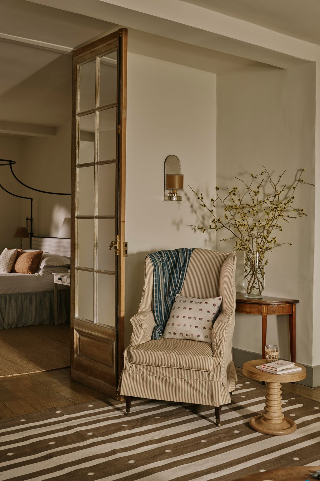 A Spanish silver plate wall light sits above an antique demi lune table. The antique textile cushion with cherries is...