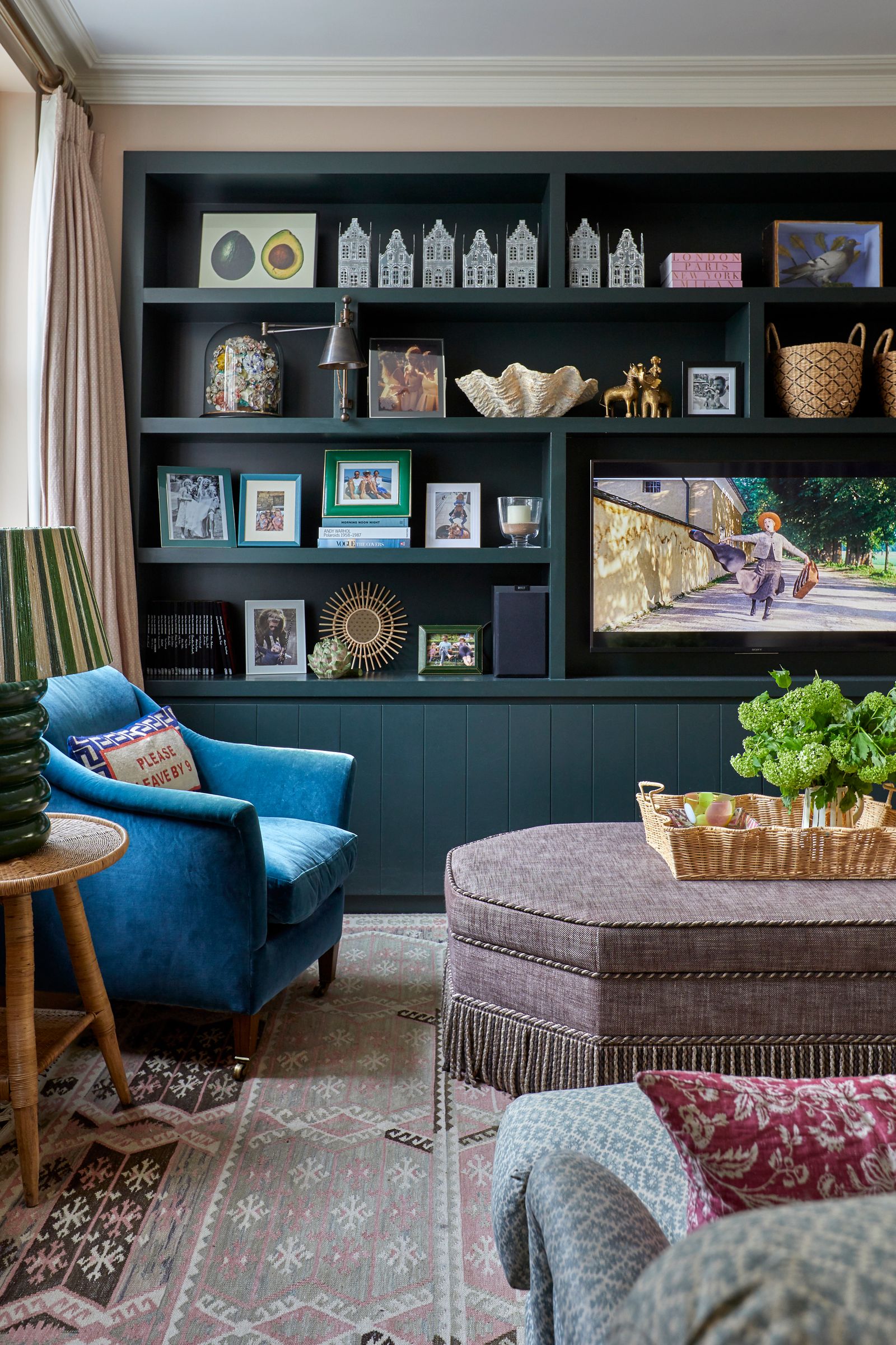 An ottoman from Clock House Furniture is at the centre of the sitting area which has builtin shelving painted in Farrow...