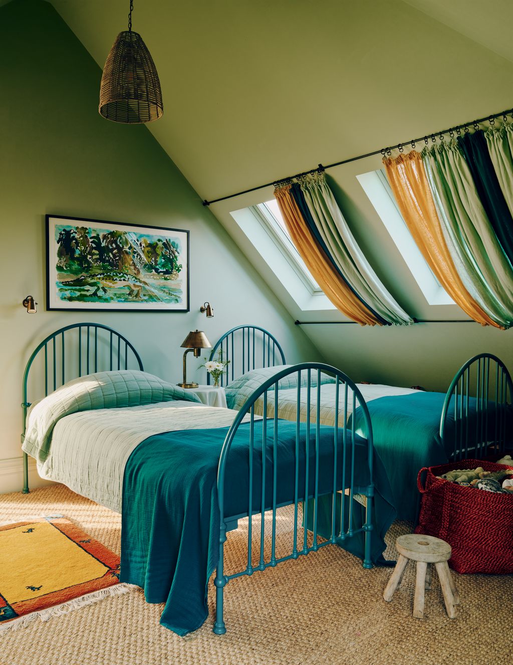 A twin room features pale green walls and vibrant beds.