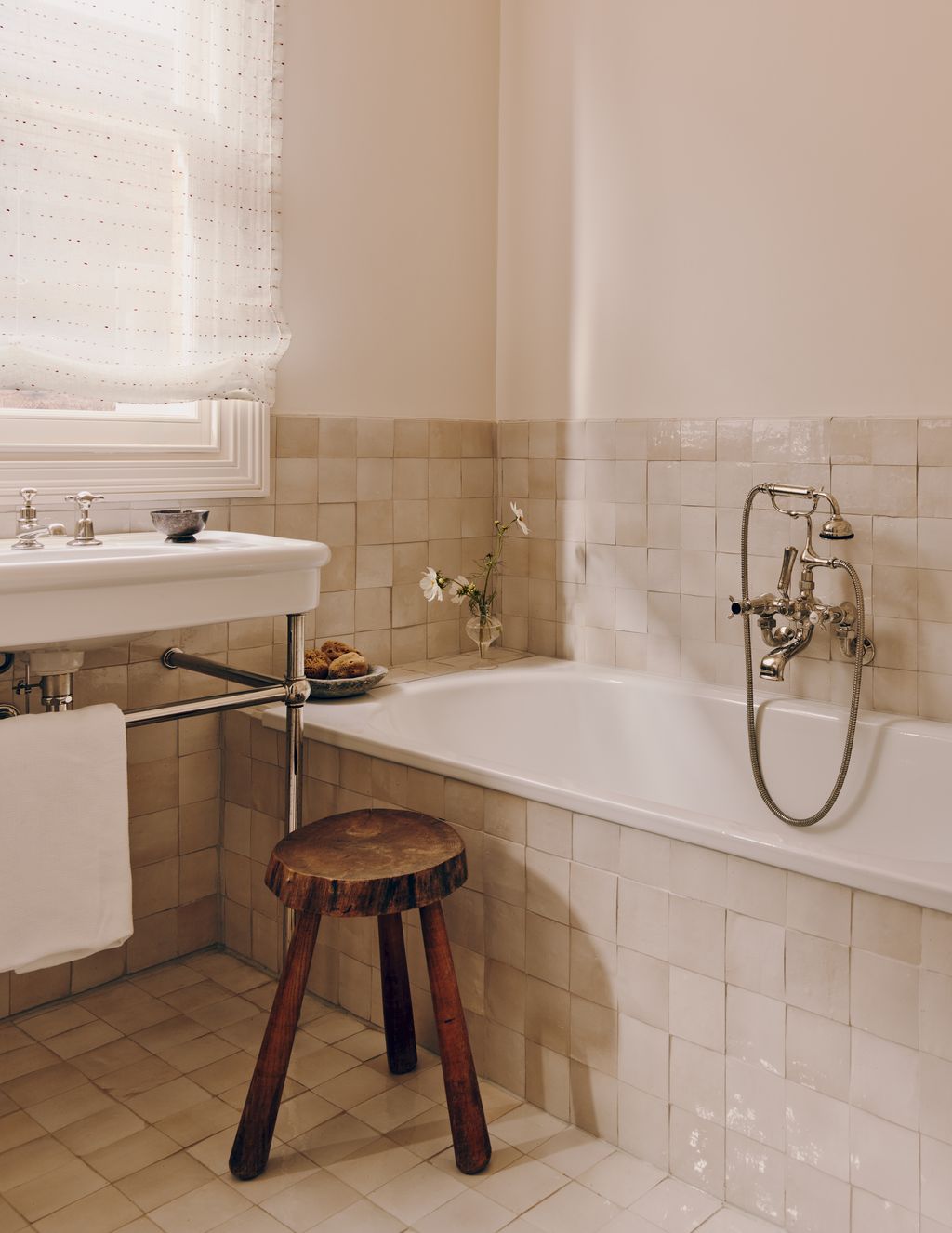 A bathroom features zellige tiles and an airy blind.