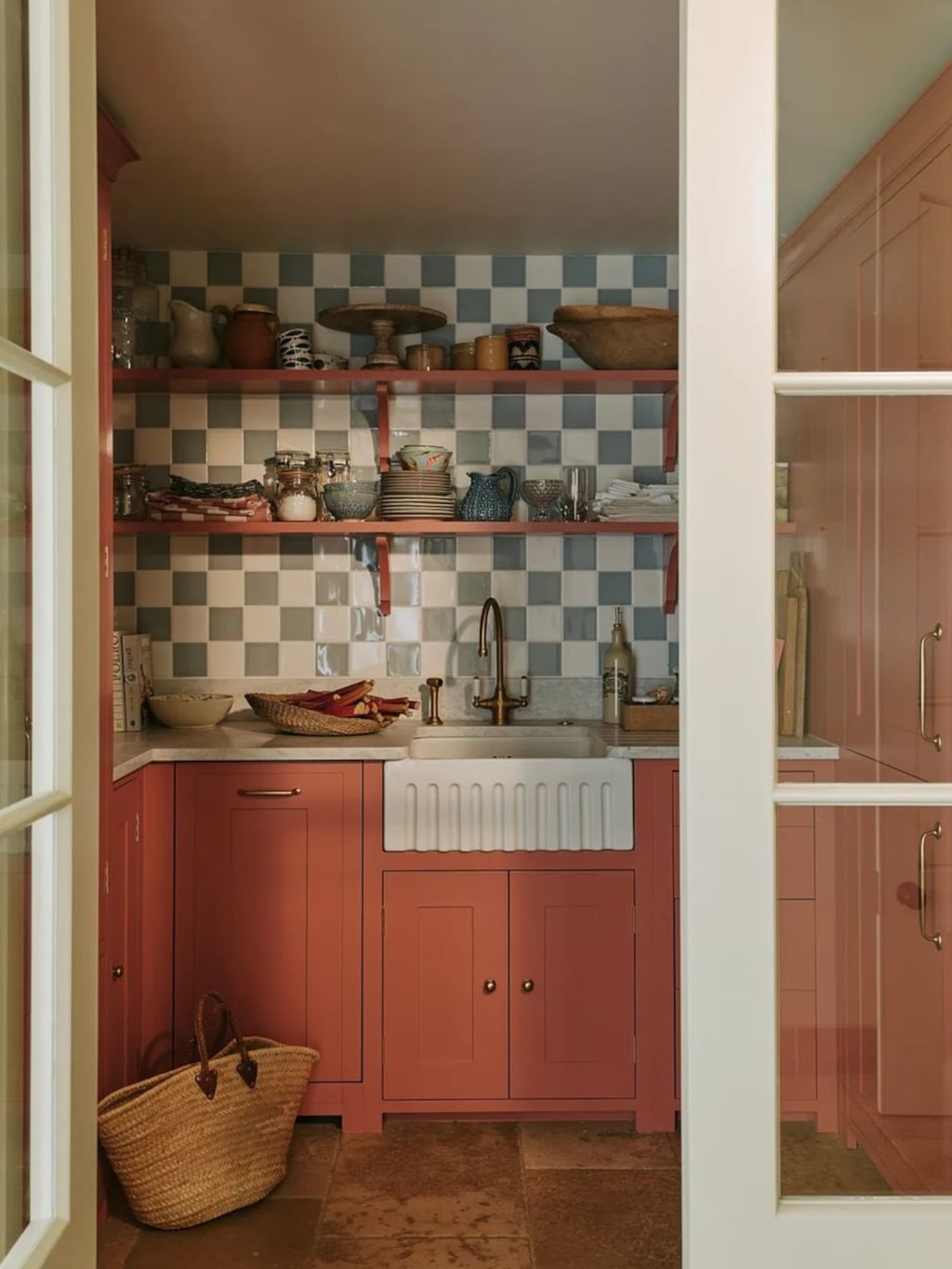 The bright paintwork and chequerboard tiles bring this functional pantry space to life. A traditional butler sink with a...