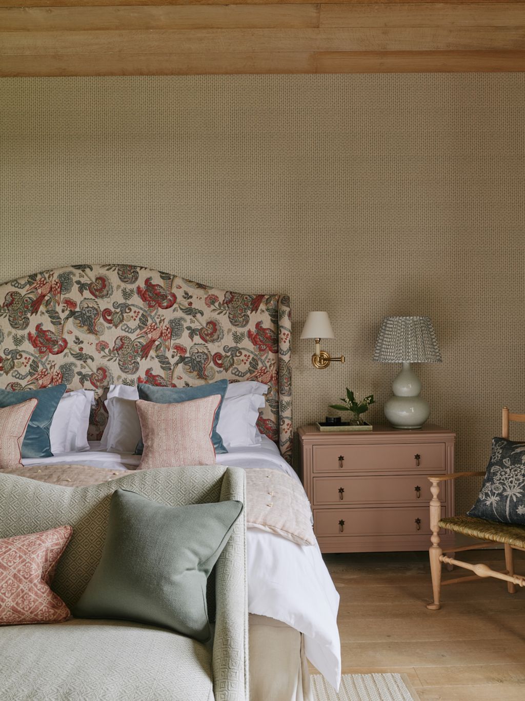 In the main bedroom a headboard covered in Ian Sandersons ‘Poppinjay linen tones with pale pink bedside tables from...